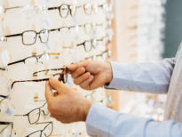 closeup of man choosing glasses in optic store. detail of hands